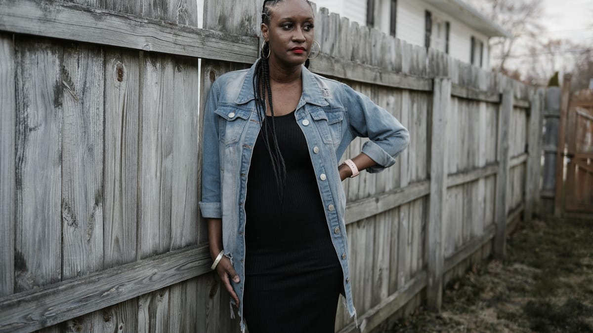 A denim jacket layered over a black midi dress, a classic transitional combination that handles cool mornings and warmer afternoons