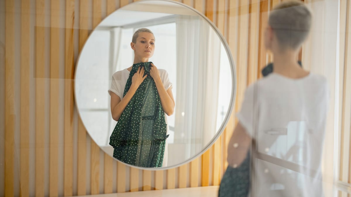 Woman evaluating outfit options in front of a mirror